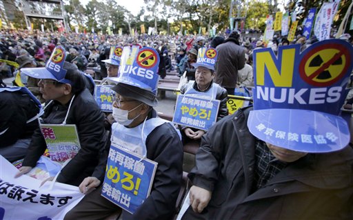 2013 оны 12 сарын 22. Цөмийн эсрэг тэмцэгчид Токиод эсэргүүцлийн цуглаан дээр. Парламентийн ордонгийн гадна мянга гаруй хүн цугларч цөмийнэ рчим хүчнээс татгалзаж, 2011 оны Фукушимагийн гамшгийн дараа хаасан АЦС-уудыг дахин ажиллуулахгүй байхыг шаардаж байна. Жагсагчдын зүүсэн плакат нь Цөм хэрэггүй, АЦС бүү ажиллуул гэжээ. (Ассошиэйтид Пресс агентлаг)  